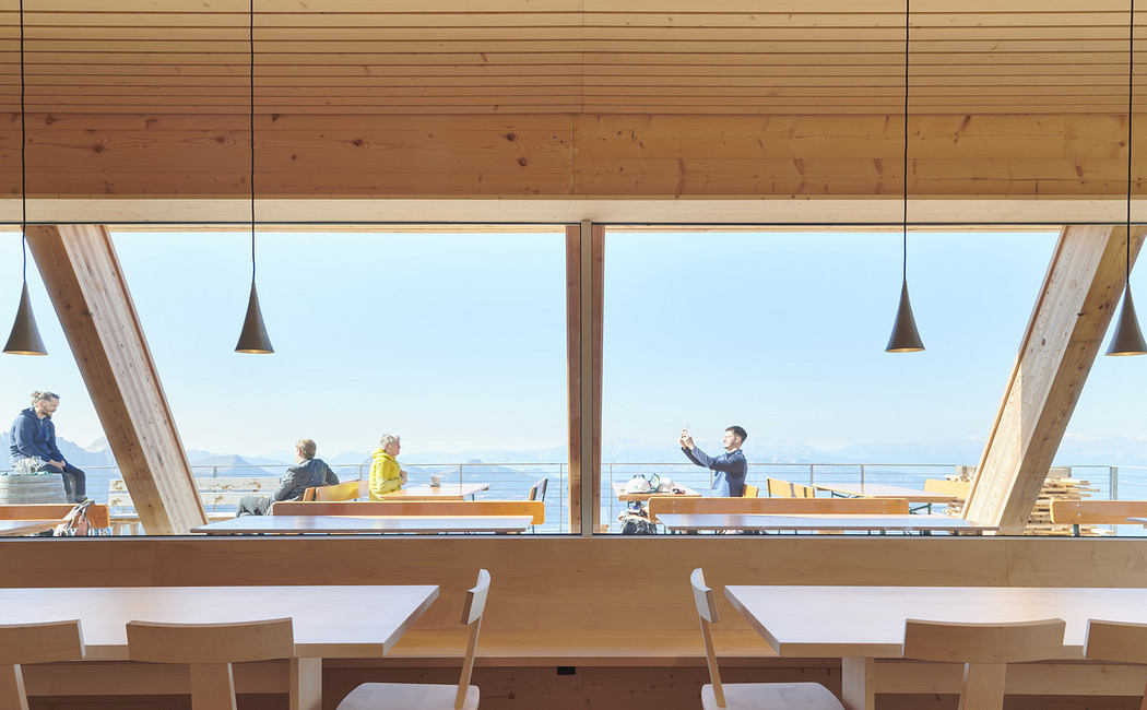 Minimalist wooden café interior with large windows and a scenic view.