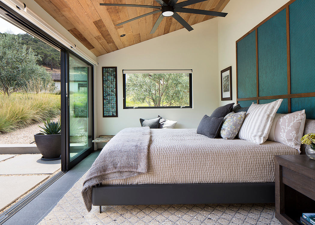 Modern bedroom with large bed, ceiling fan, and glass sliding door leading outside.