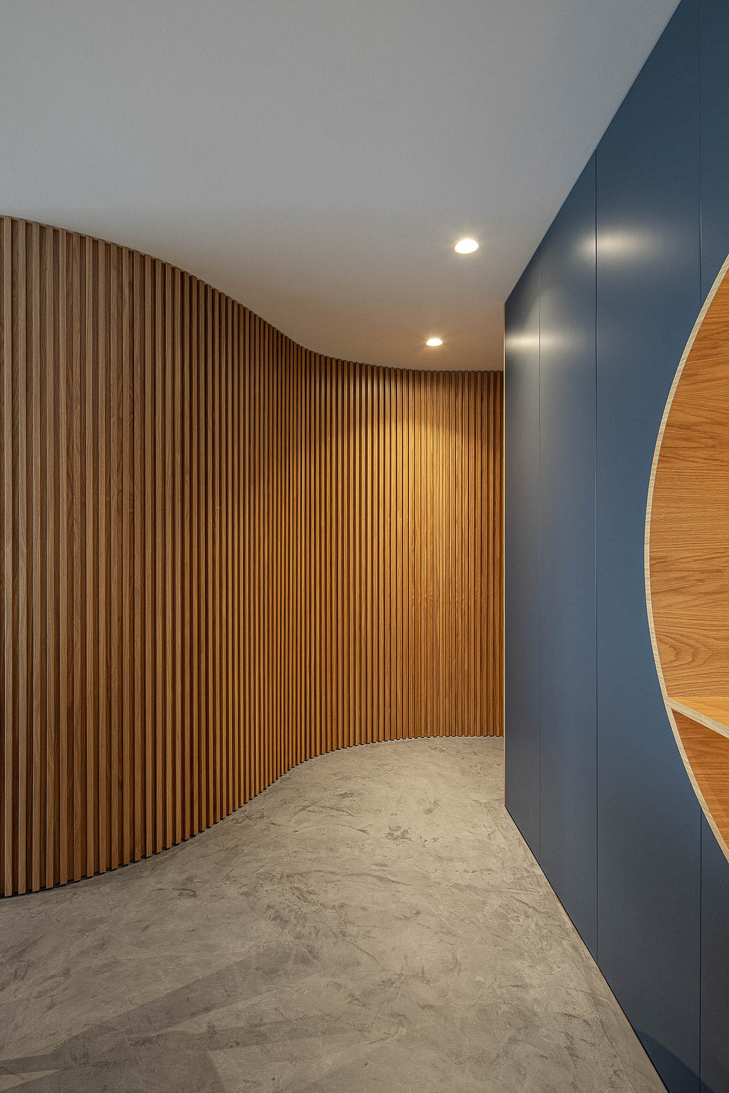 Modern corridor with curved wooden slats and blue walls.