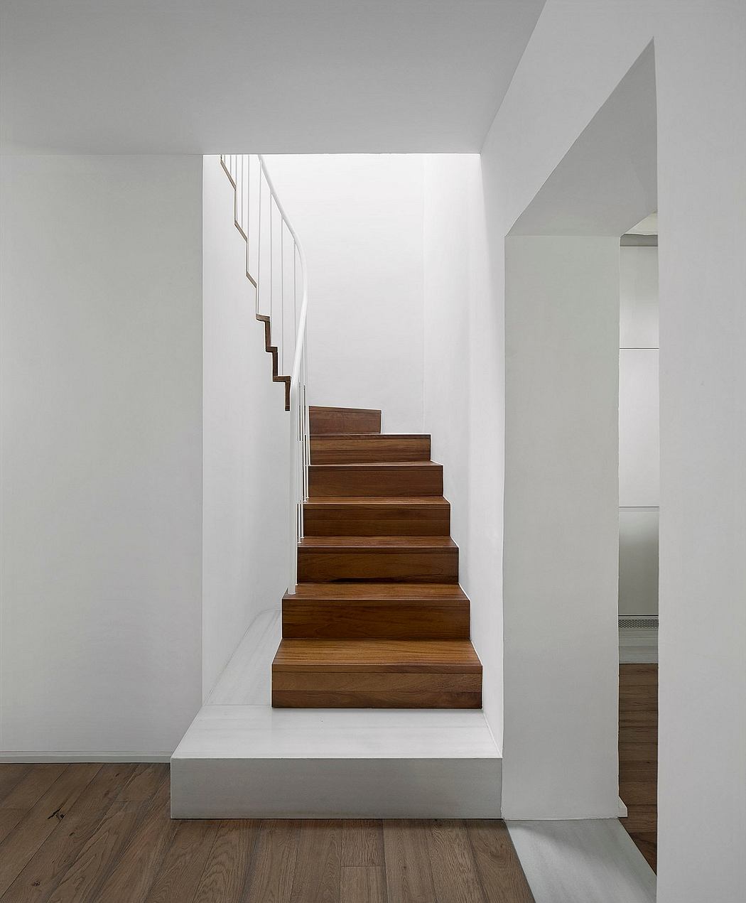 Minimalist wooden staircase with white walls and clean lines.