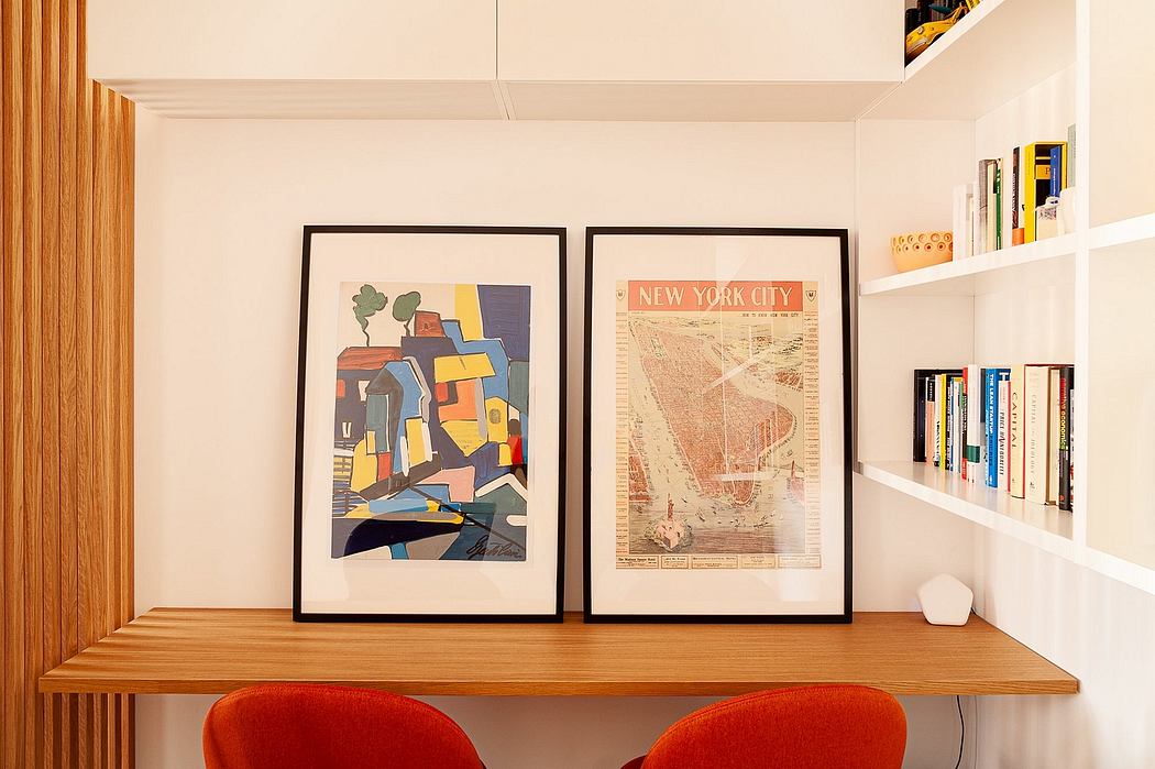 Contemporary study nook with framed art, orange chairs, and bookshelf.