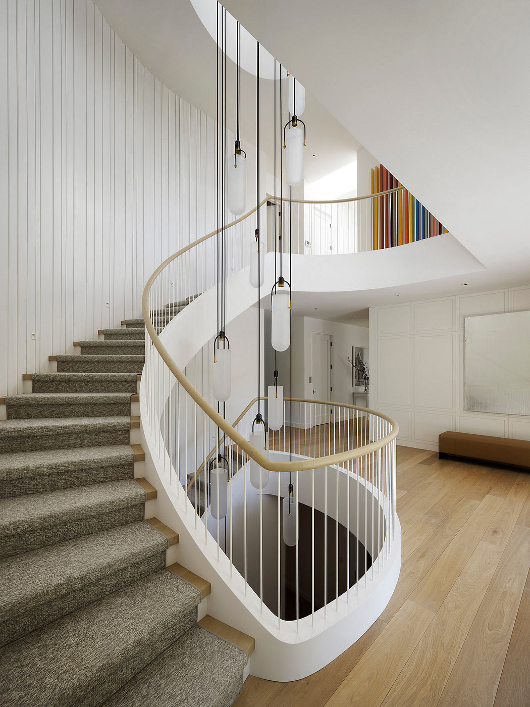 Modern spiral staircase with white balustrade and wooden steps in a bright interior.