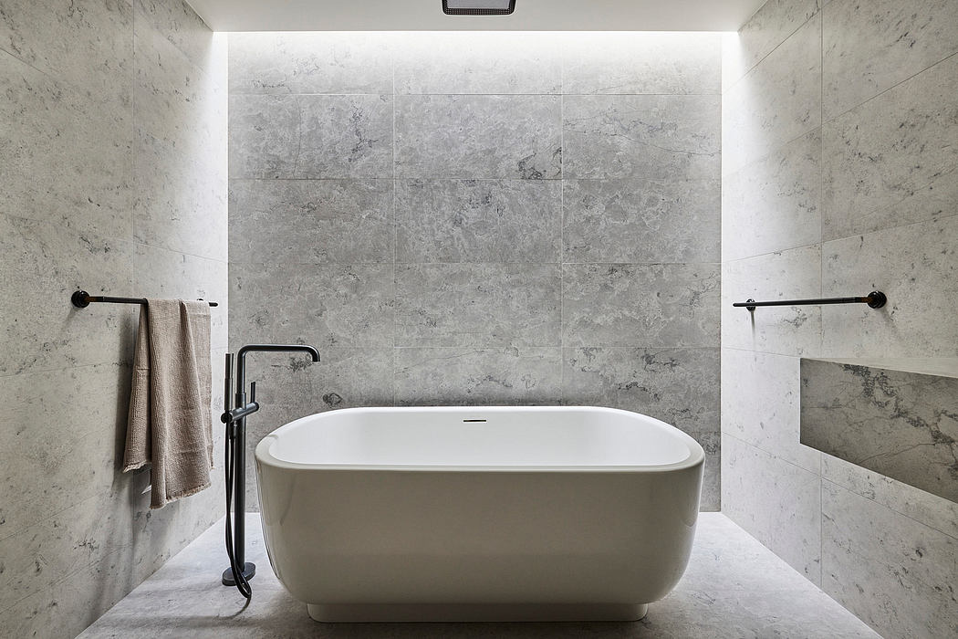 Modern bathroom with a freestanding tub and gray stone walls.