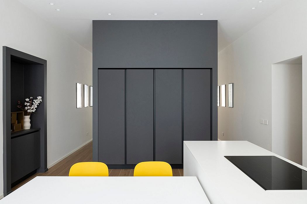 Minimalist interior with grey walls, sleek cabinets, and yellow chairs.