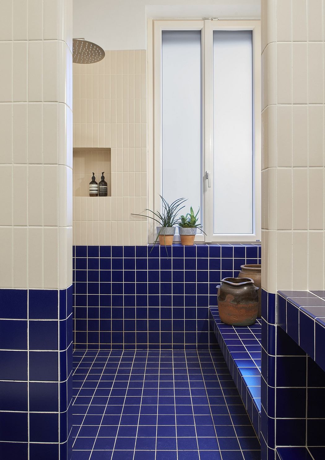 Modern bathroom with blue and beige tiled walls and floor.