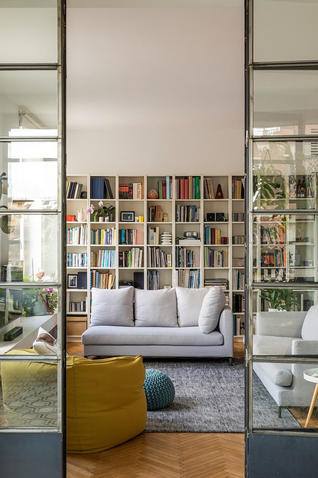 Contemporary living room with floor-to-ceiling bookshelves seen through glass doors