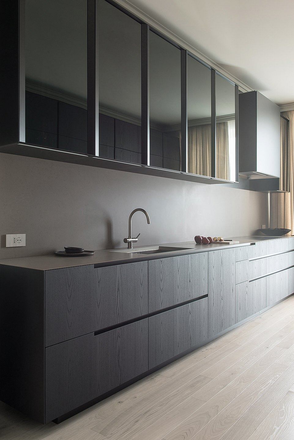Sleek grey kitchen cabinetry with minimalist design and wood flooring.