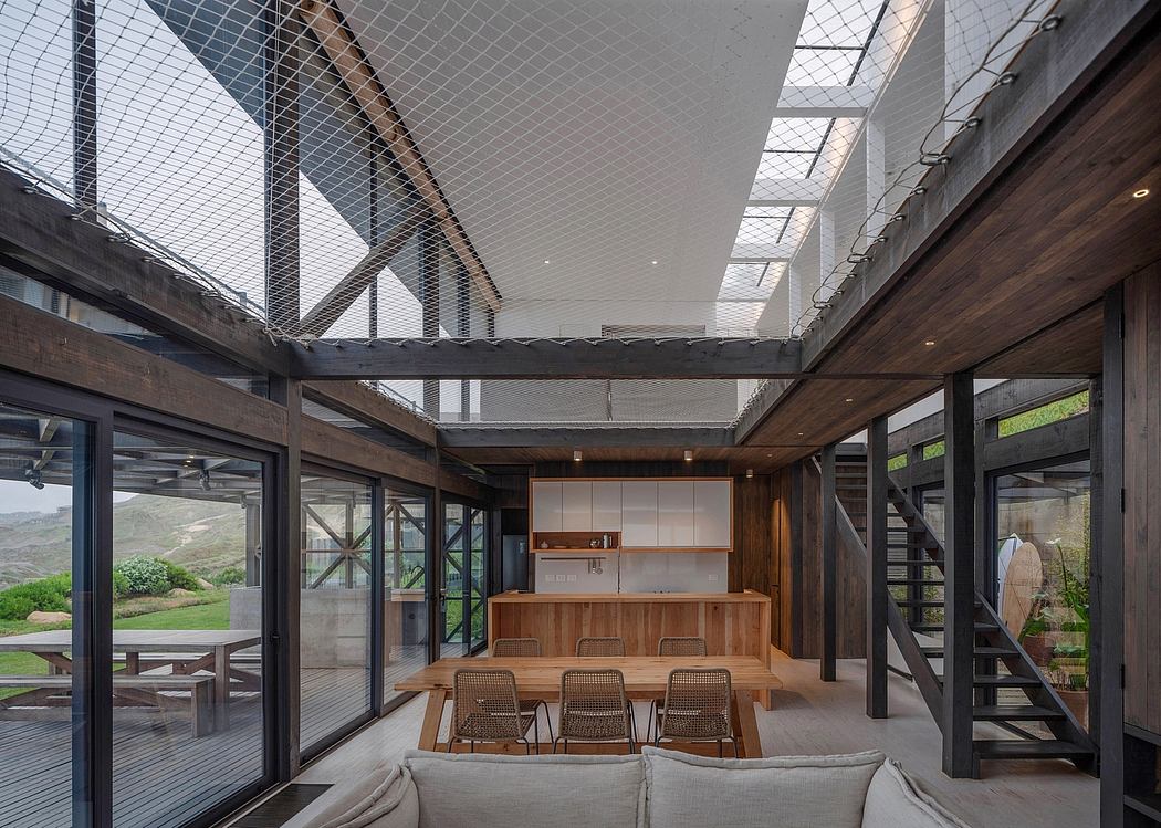 Open-plan living space with expansive glass walls and a high, netted ceiling.