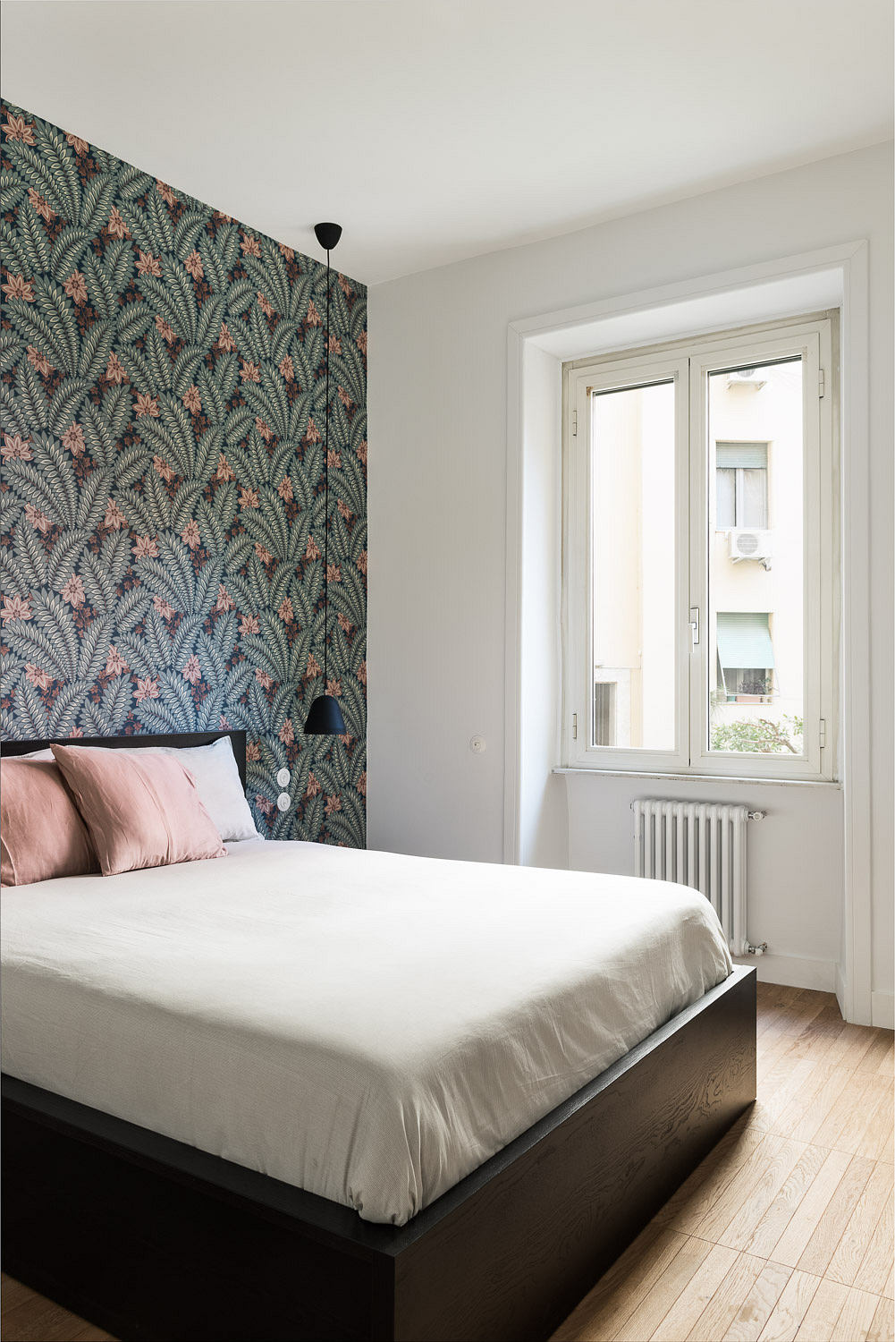 Contemporary bedroom with vibrant tropical wallpaper and minimalistic design.