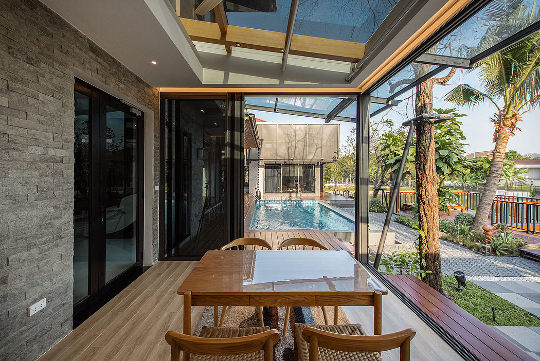 Modern dining area with glass walls overlooking a swimming pool.