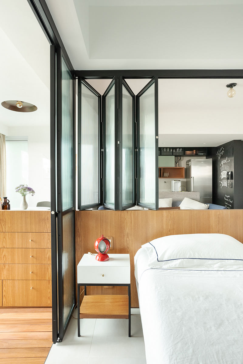Contemporary bedroom with glass partition and adjoining kitchenette.