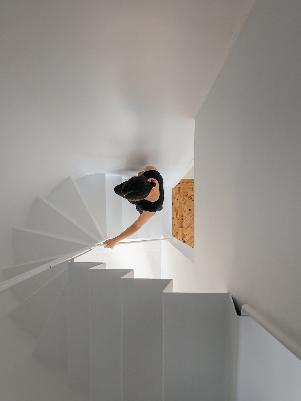Minimalistic white staircase with a person descending.