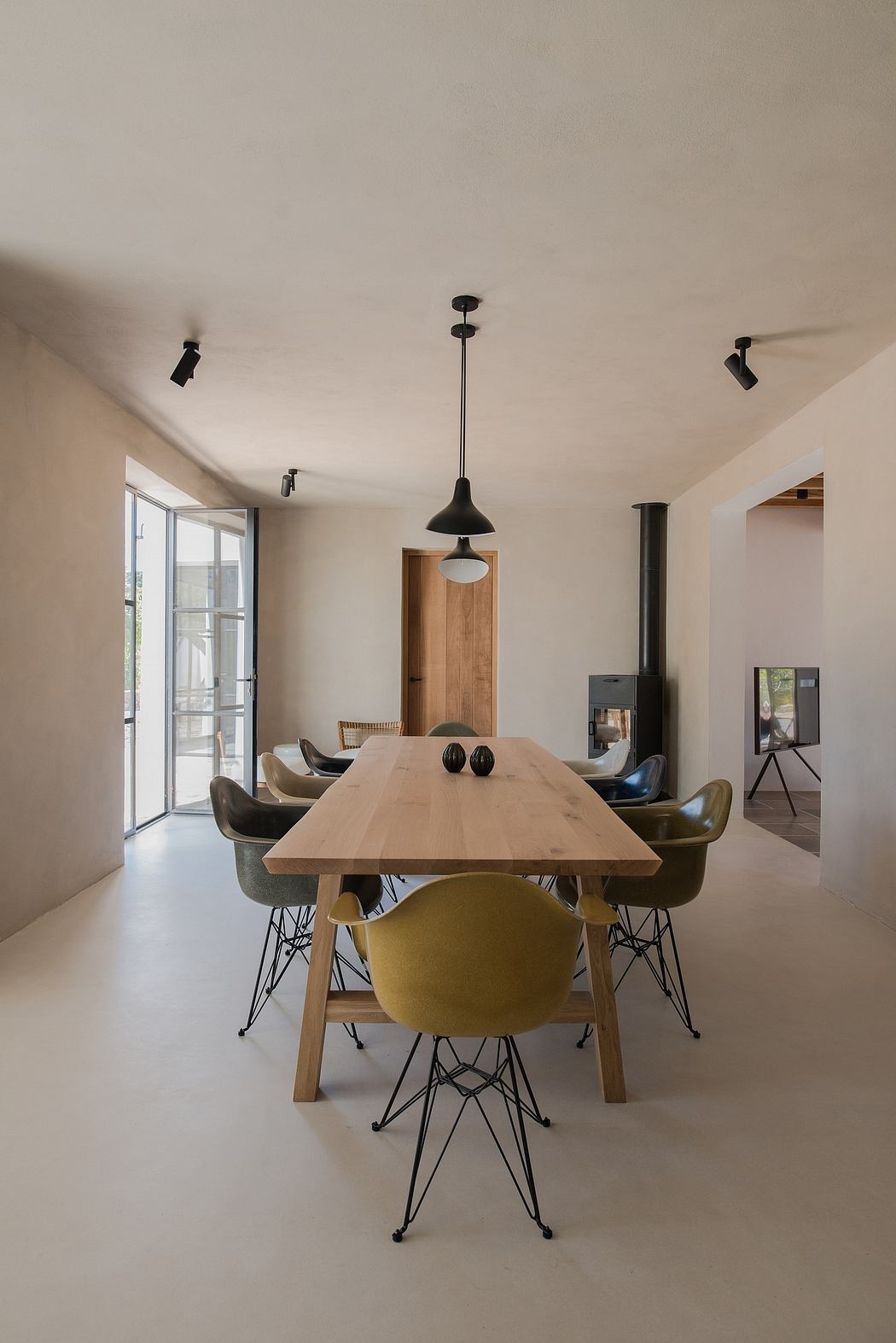 Minimalist dining room with a wooden table, olive chairs, and pendant lighting.