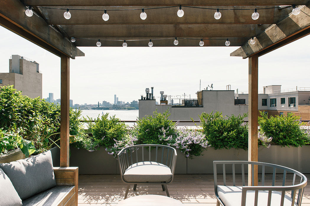Cozy rooftop patio with seating, plants, and string lights.