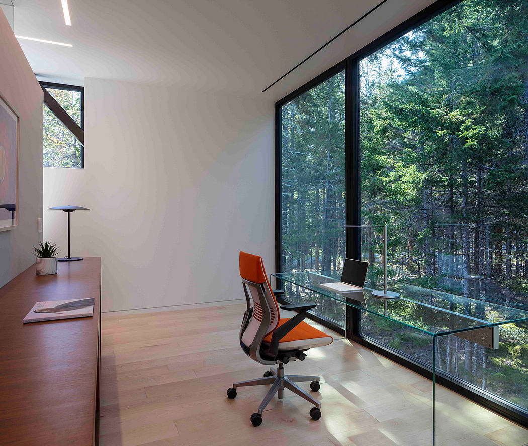 Modern home office with large window overlooking a forest.