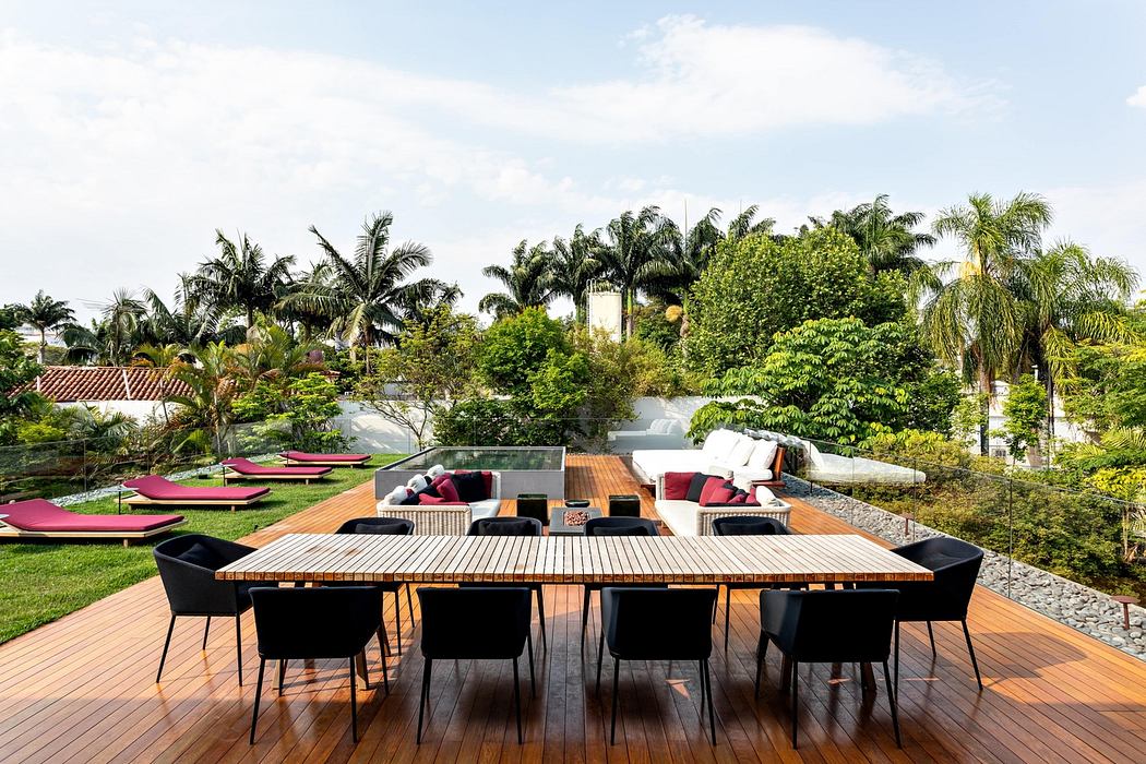 Outdoor patio with a large dining table, chairs, and lounge area surrounded by green