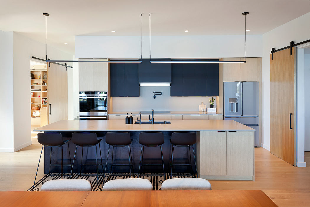 Modern kitchen with island, bar stools, and pendant lights.