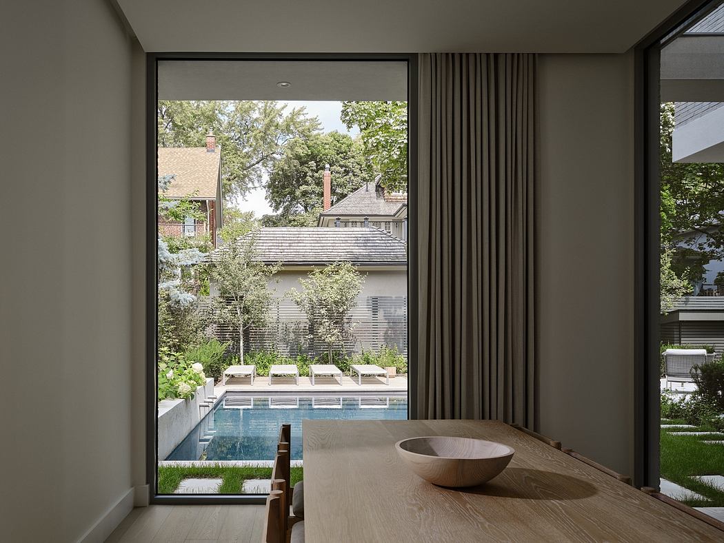 Modern room with large window overlooking a pool and garden.