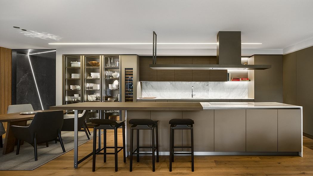 Contemporary kitchen with island, bar stools, and integrated lighting.