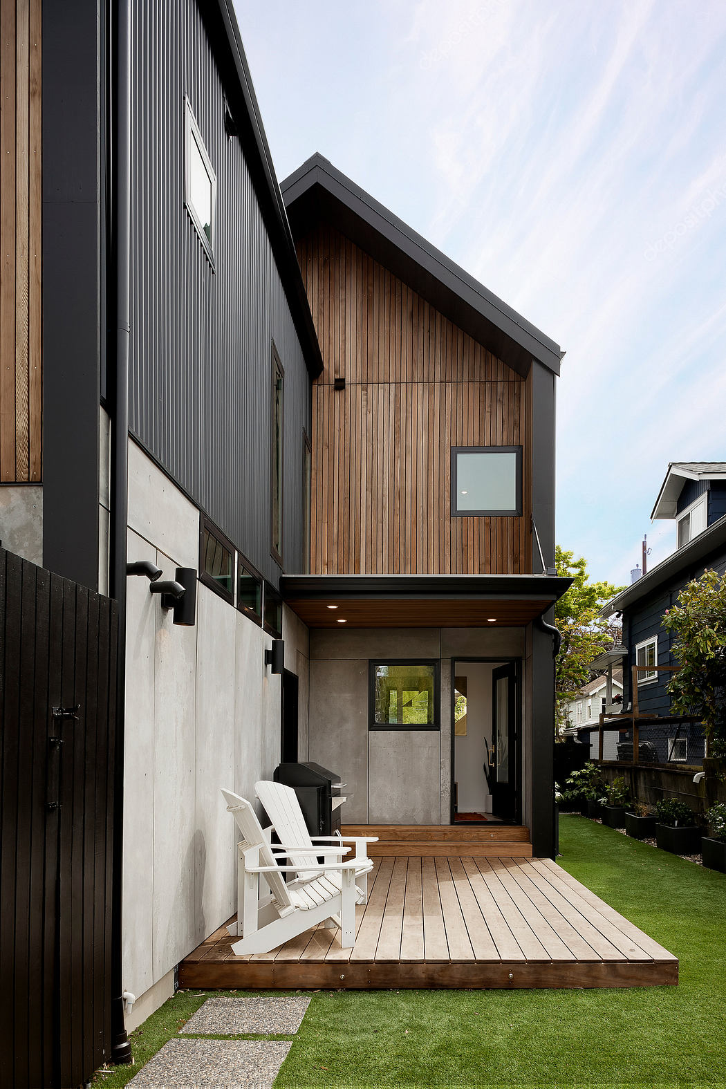 Contemporary two-story home with wood and black paneling, and a cozy front