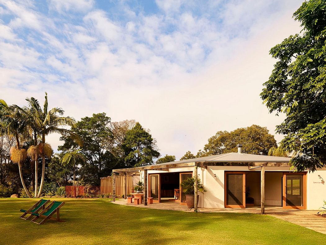 Contemporary single-story house with large garden and deck chairs.