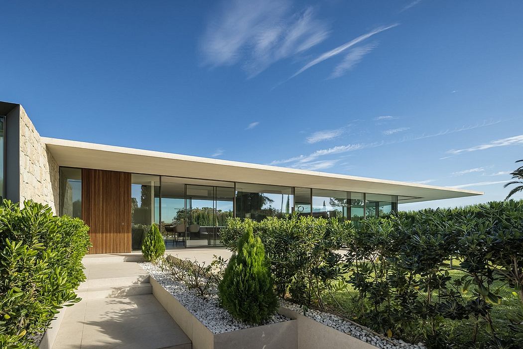 Contemporary house with flat roof and expansive glass walls surrounded by greenery.