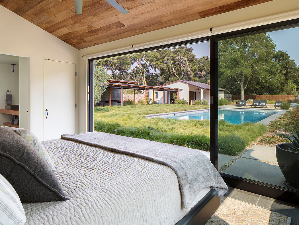 Contemporary bedroom with large windows overlooking a pool.