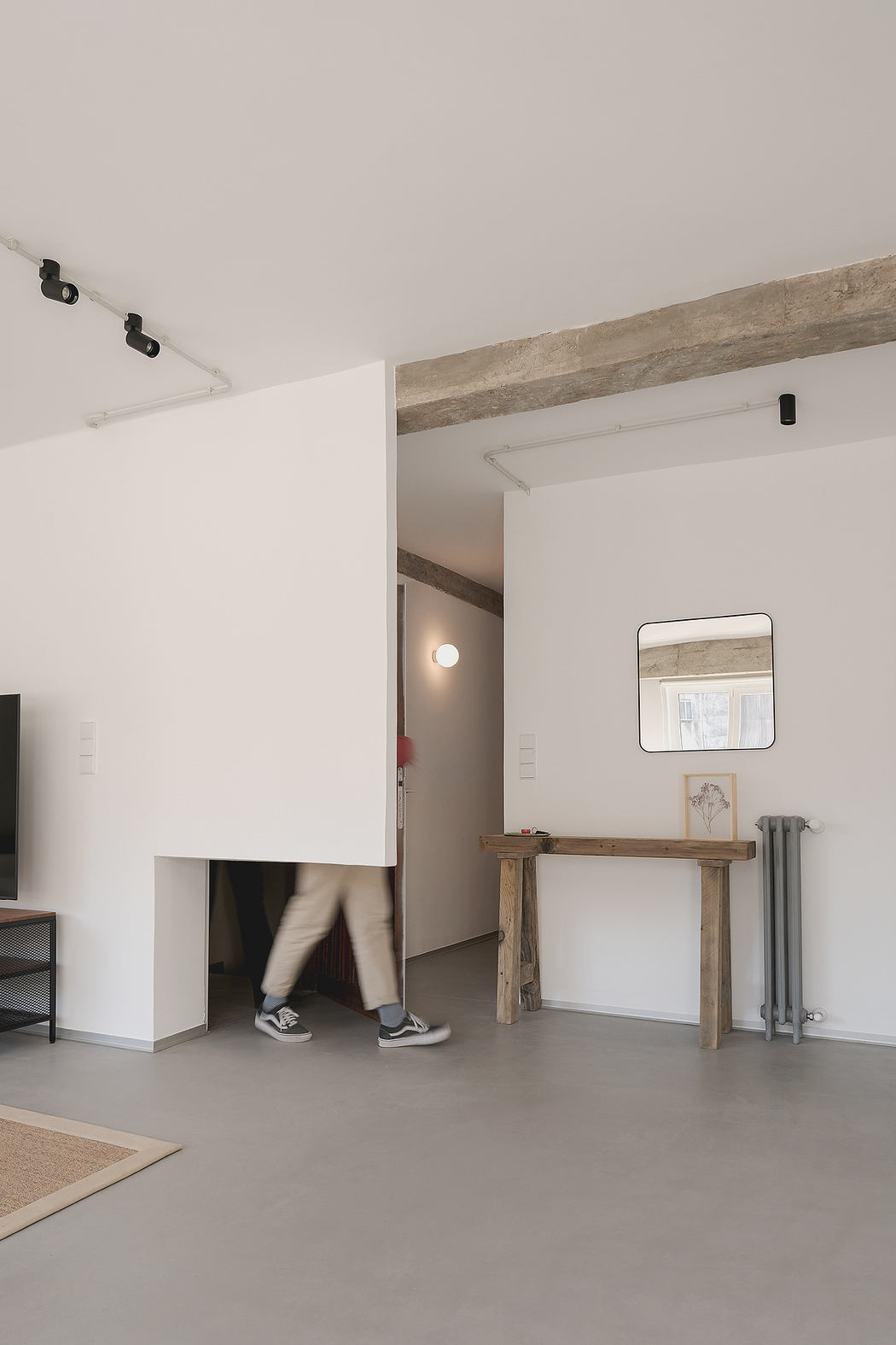 Minimalist interior with white walls, exposed beams, and a rustic table.