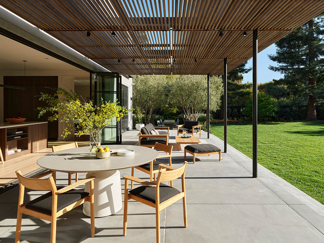 Modern outdoor patio with furniture, overhanging slats, and a garden view