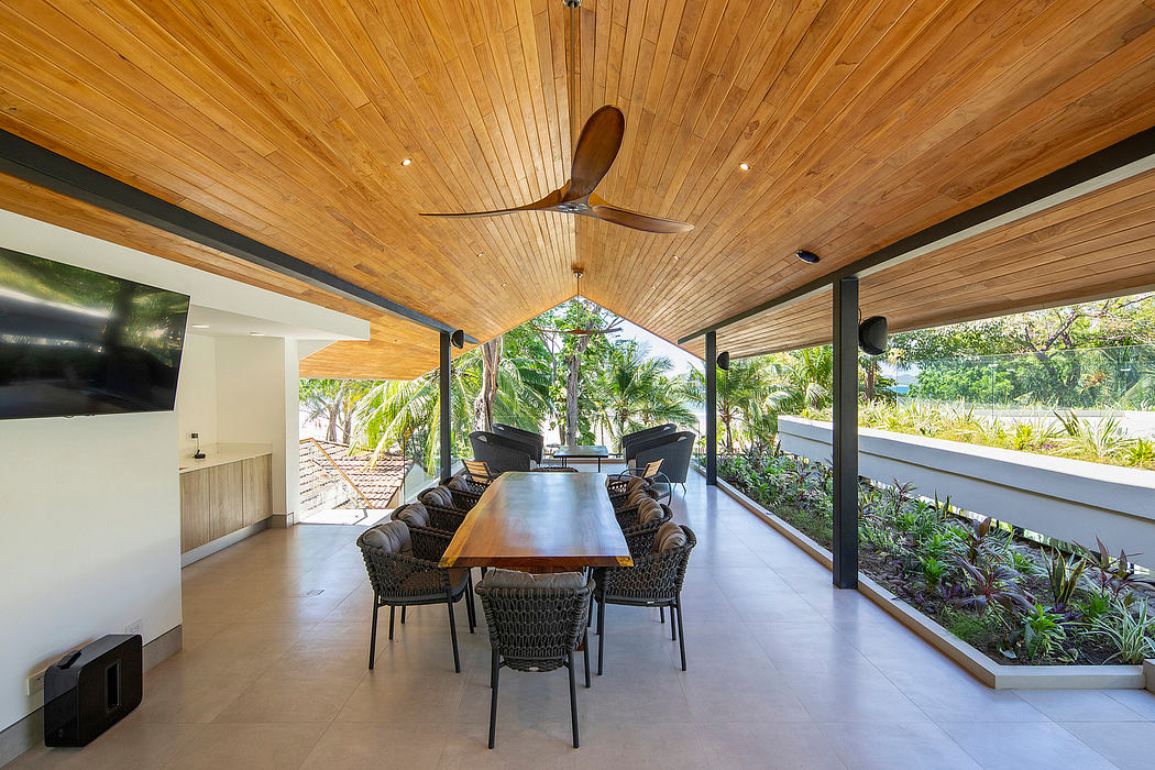 Sleek open dining space with wooden ceiling and tropical view.