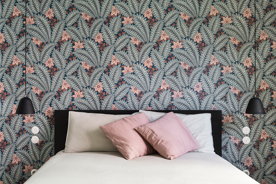 Chic bedroom with tropical wallpaper and sleek wall lamps.