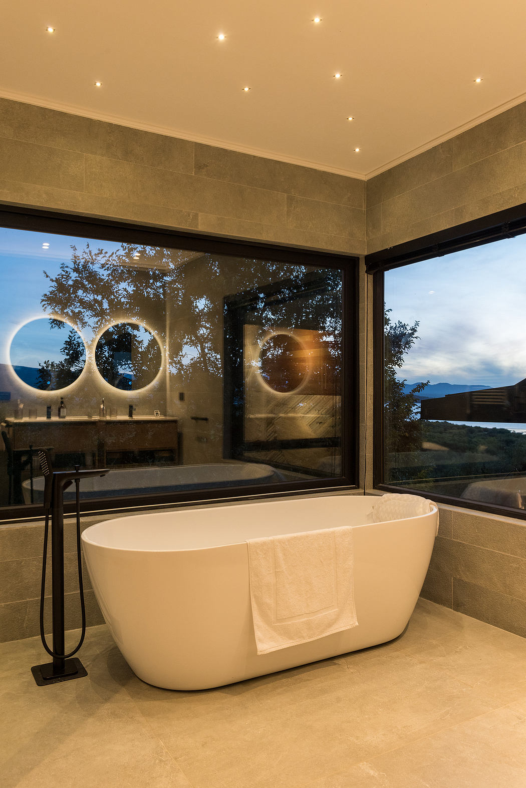 Modern bathroom with freestanding tub, large window, and star-like ceiling lights