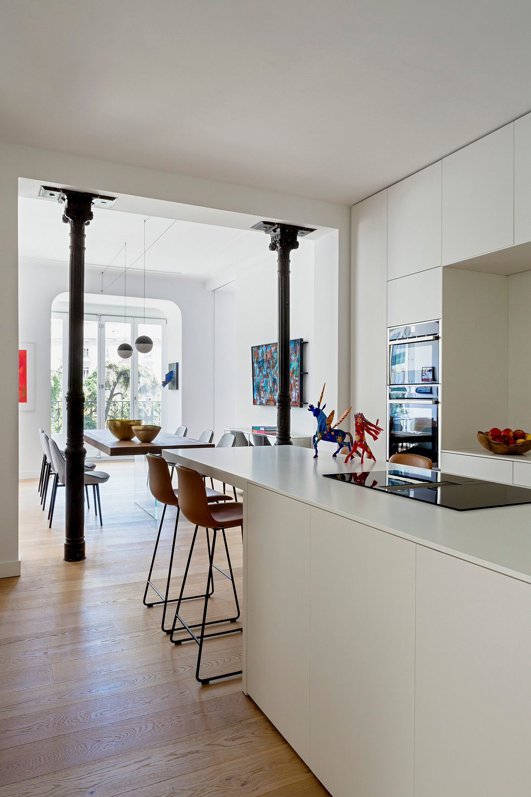 Modern kitchen with white cabinetry and dining area with black columns.