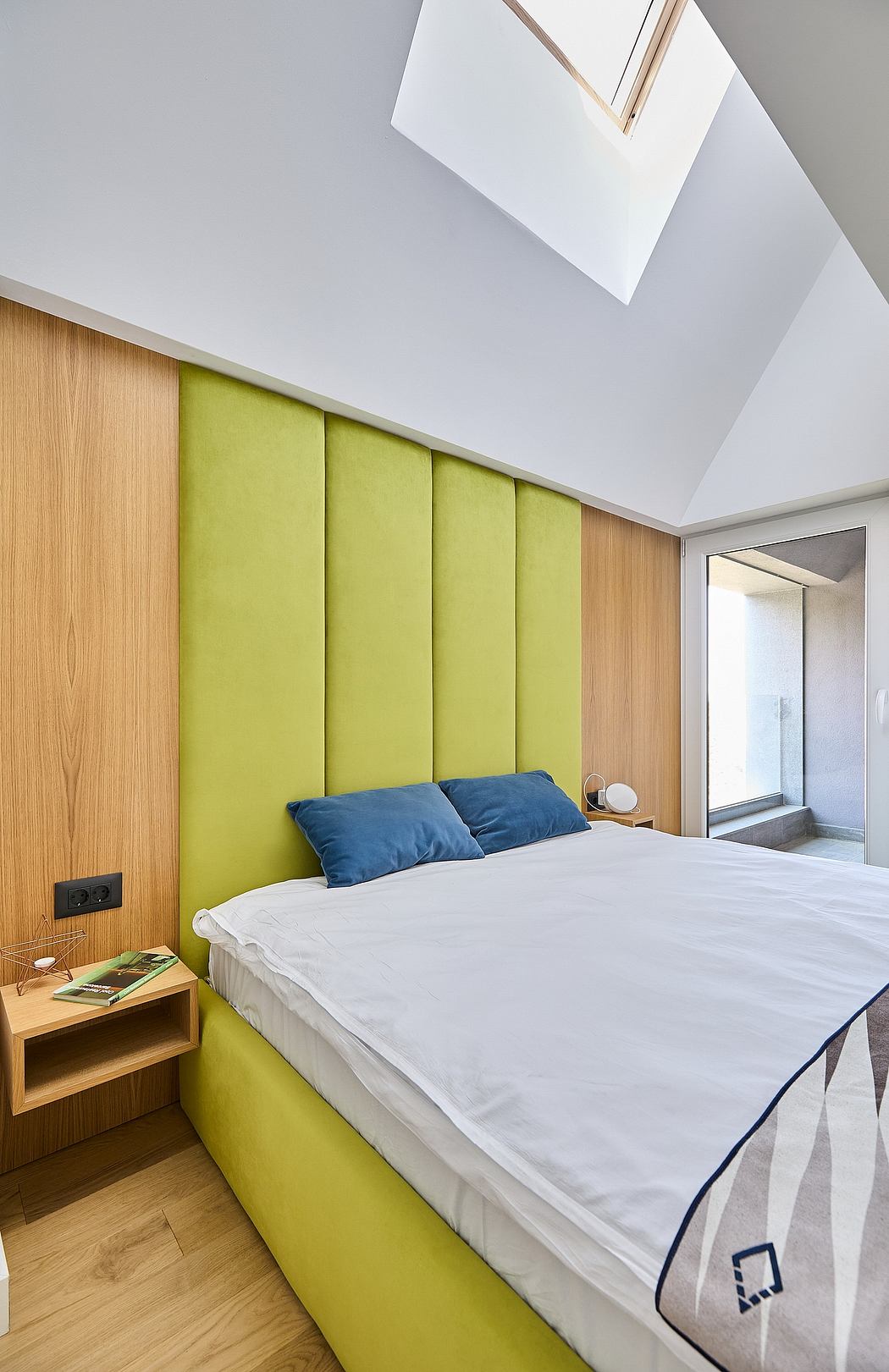 Minimalistic attic bedroom with lime green headboard and skylight.