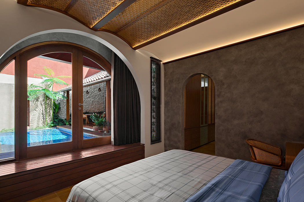 Contemporary bedroom with arched window overlooking a pool.
