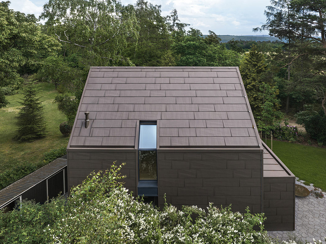 Modern house with a symmetrical sloped roof surrounded by greenery.
