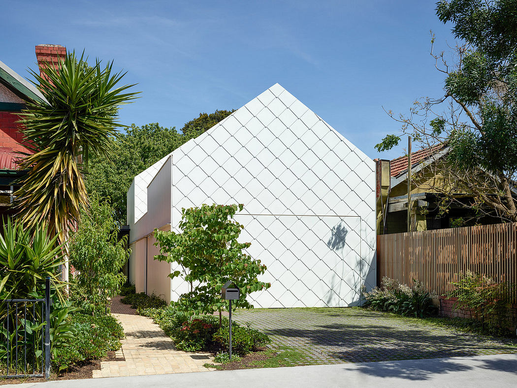 Geometric white house with a diamond-pattern facade surrounded by greenery.