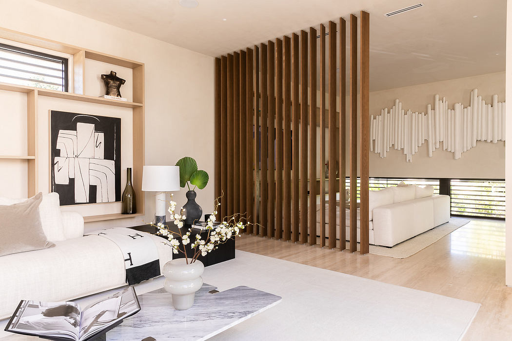Modern living room with wooden slat partition, white furniture, and abstract art.