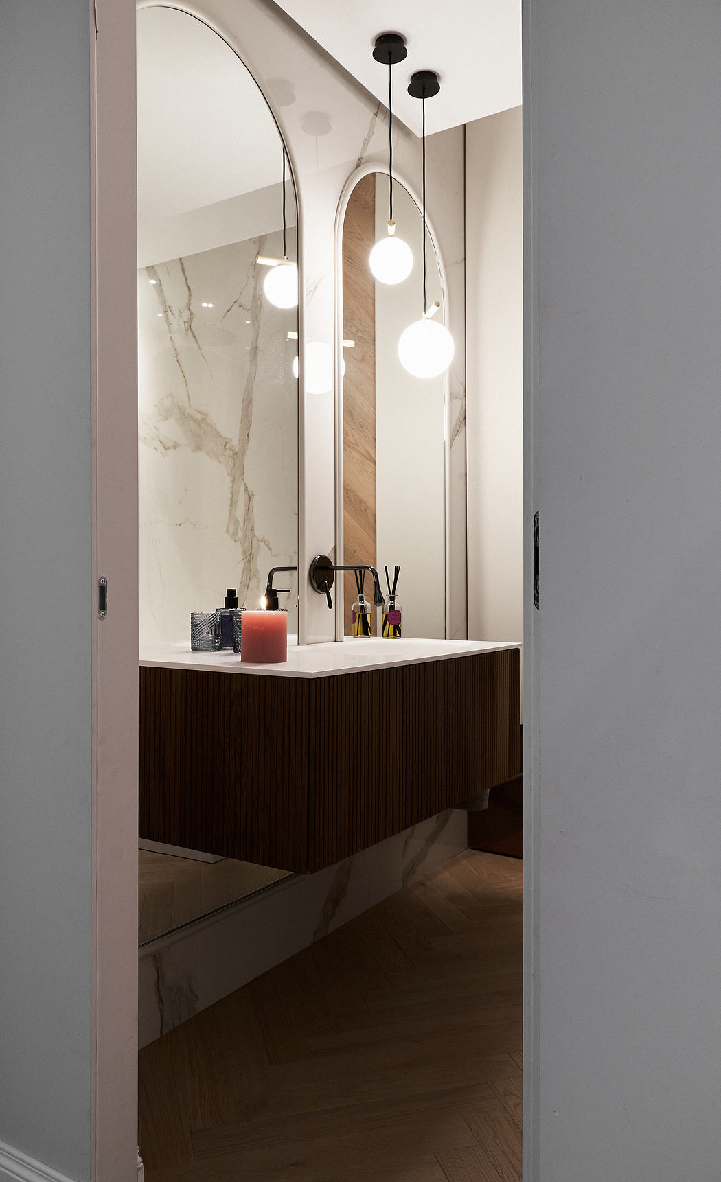 Modern bathroom with arched mirror and floating vanity.