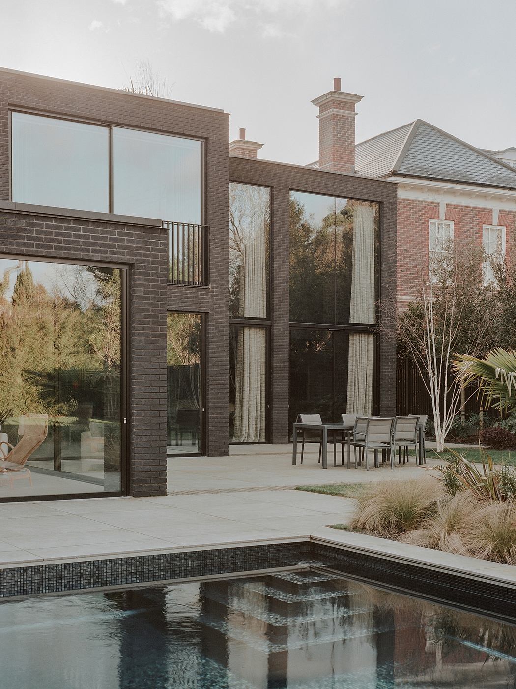 Contemporary brick home with large windows and a pool.