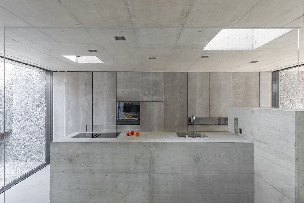 Minimalist kitchen with concrete finish and integrated appliances.