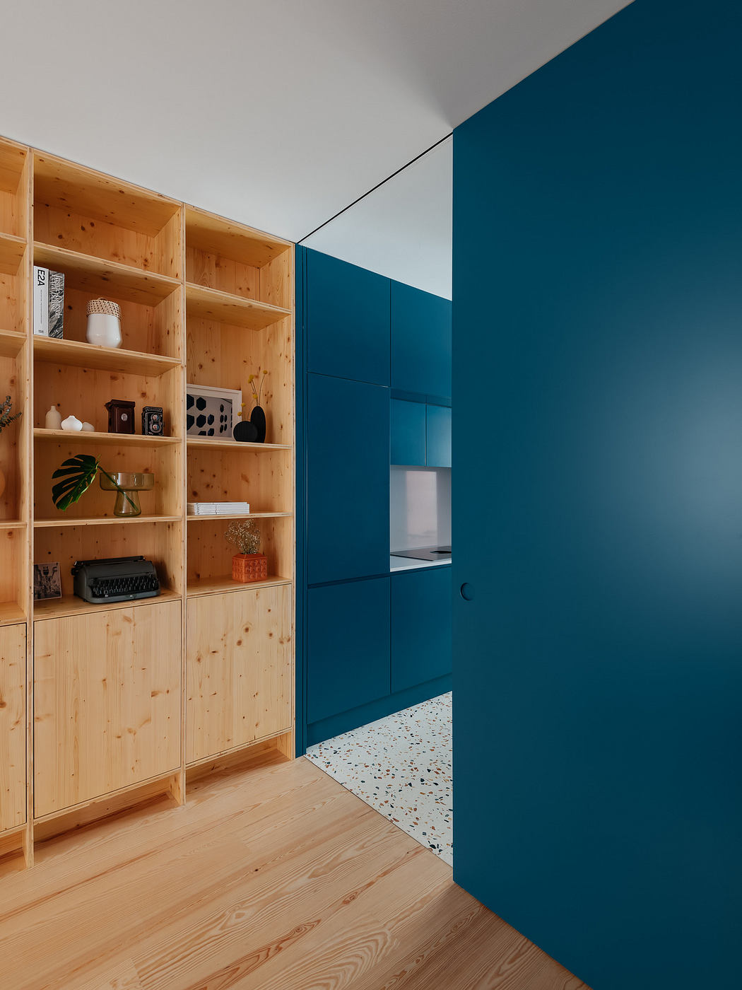 Contemporary room with bold blue wall and wooden bookshelf.