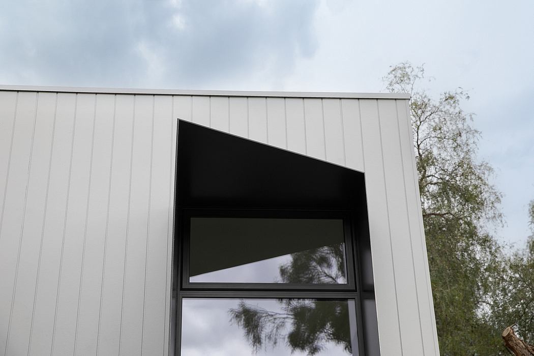 Contemporary building with an asymmetrical window design against a cloudy sky.