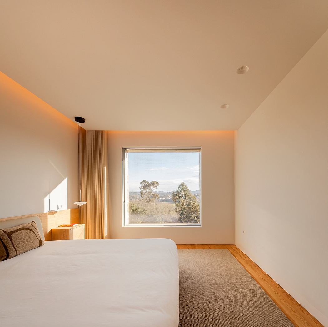 Minimalist bedroom with warm lighting and scenic window view.