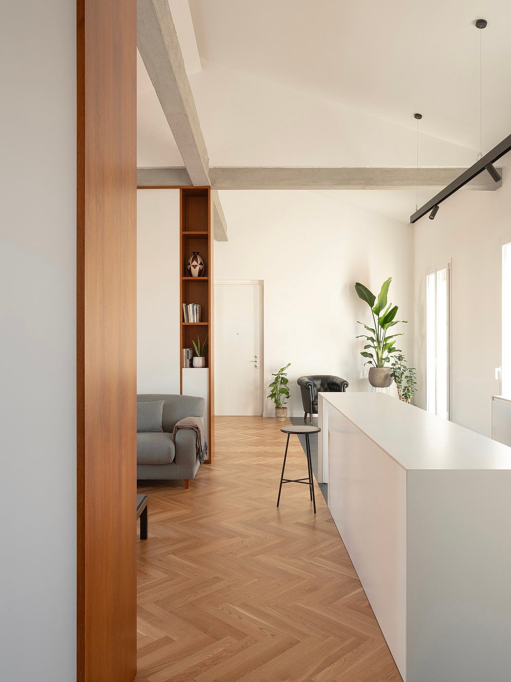 Modern interior with white walls, herringbone floor, and minimalistic furniture.