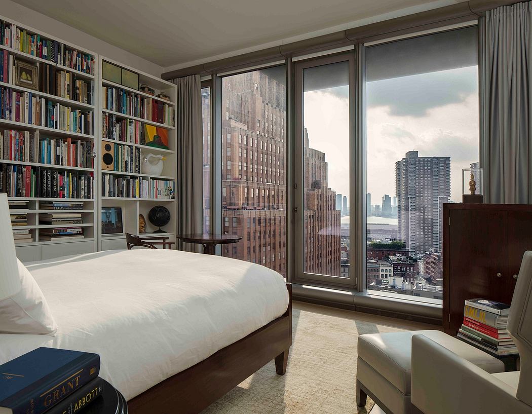 Urban bedroom with floor-to-ceiling windows and a bookshelf wall.