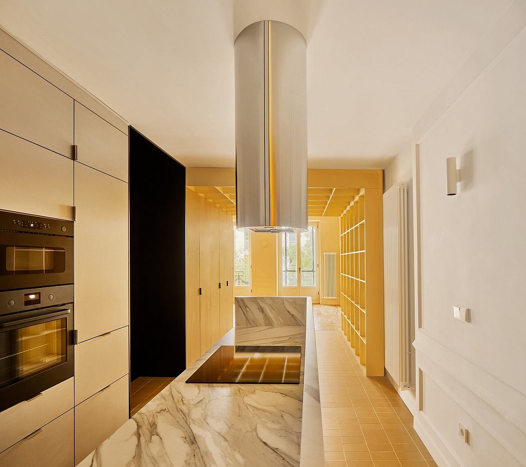 Sleek kitchen with marble floors and cylindrical exhaust hood.