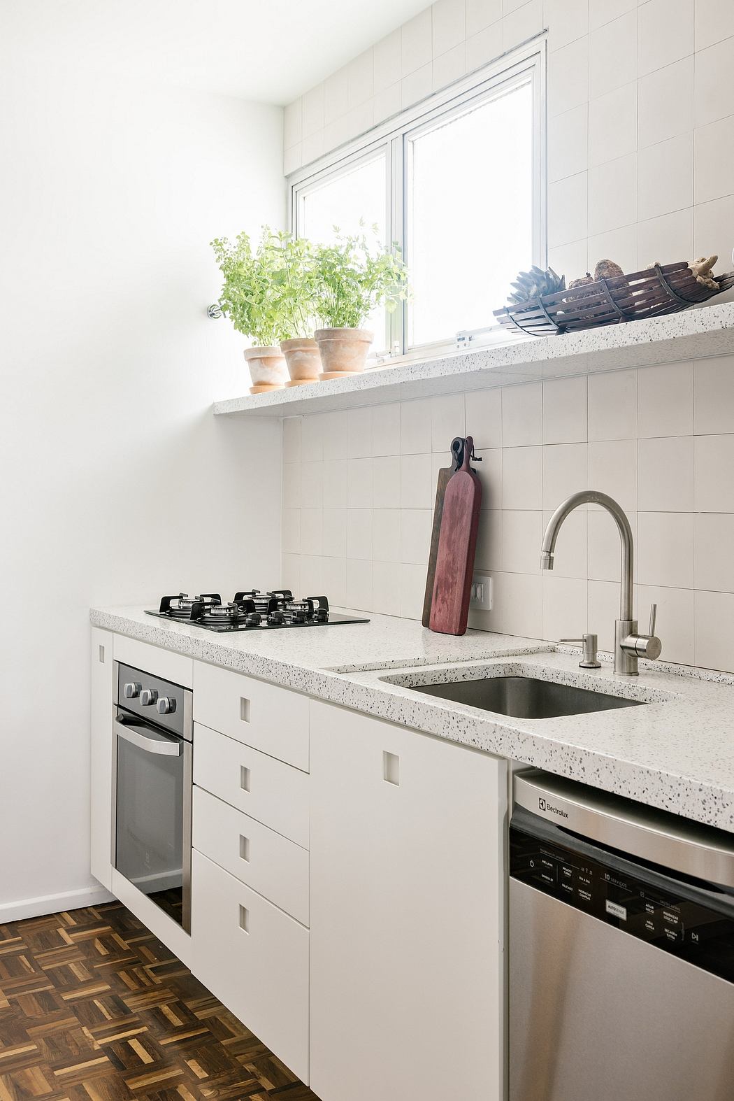 Sleek kitchen with white cabinetry, granite countertops, and parquet flooring