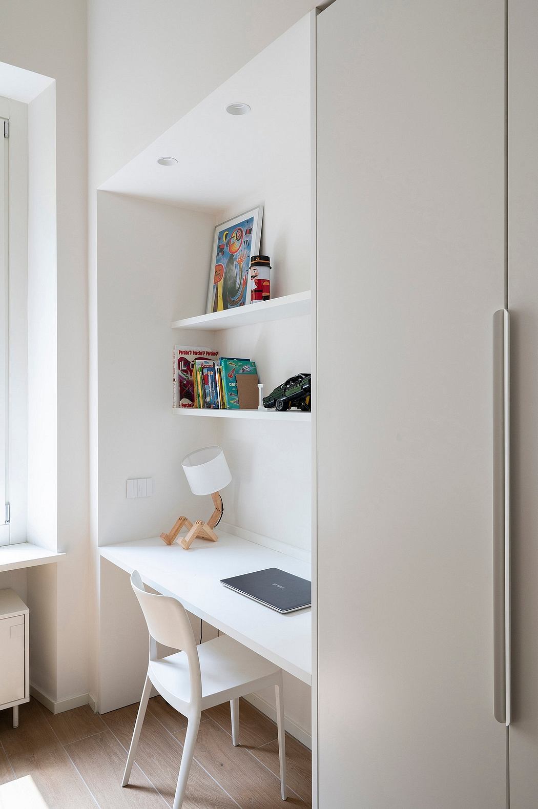 Minimalist white home office nook with built-in desk and shelves.