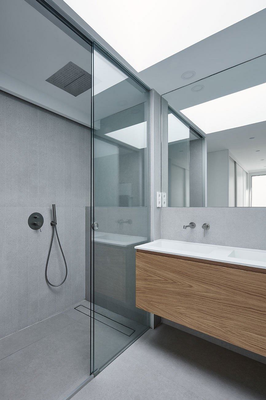 Modern bathroom with glass shower and wooden vanity.